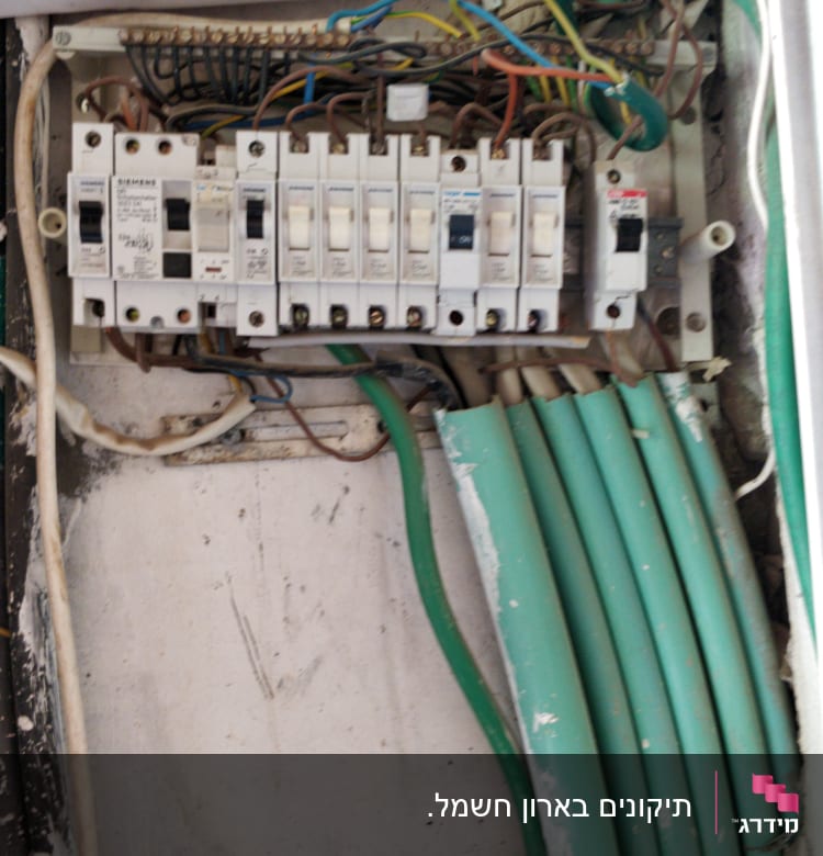 לוח חשמל עם מפסקים וחוטים חשמליים ירוקים